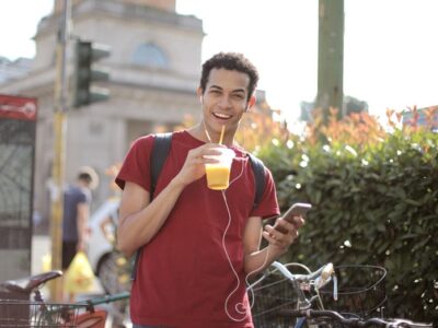 A young man listening to music on his headphones and having an orange juice.